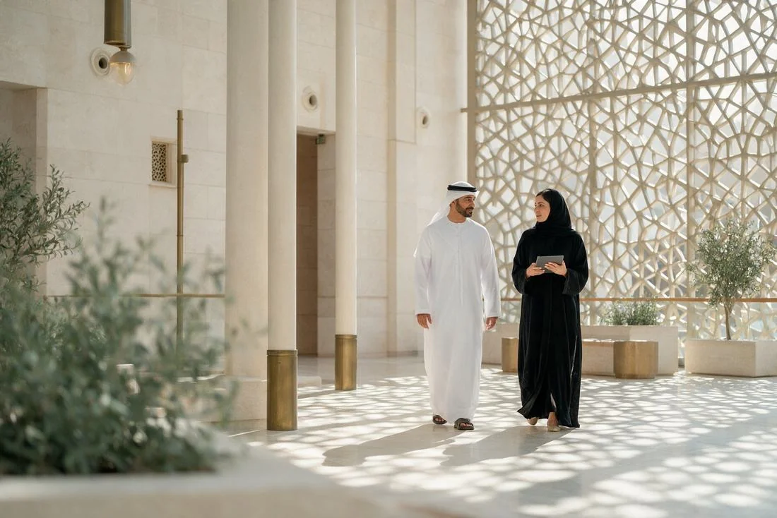 Emirati official and a colleague walking through the bright lobby of a government building